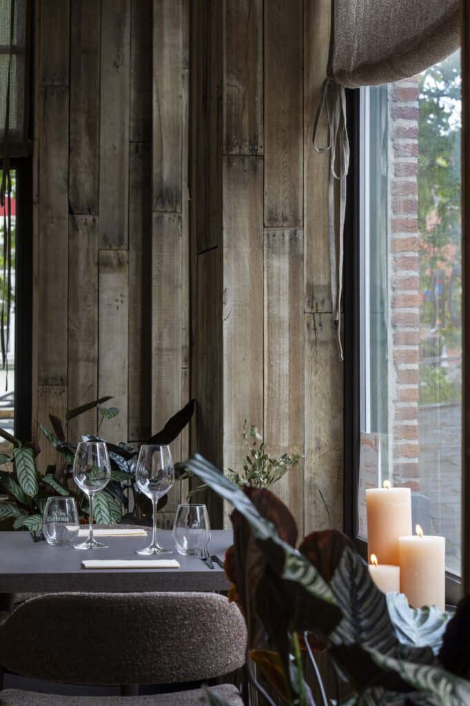 Gedekte tafel bij het raam met planten en kaarsen